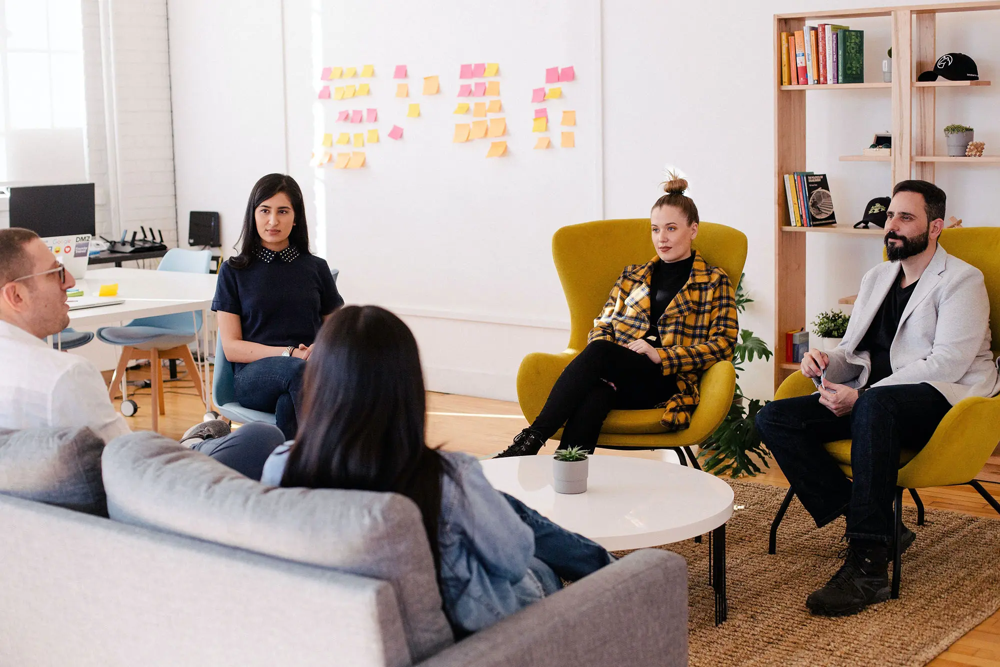 A team of 5 people sitting around a table and watching one person speak.